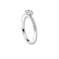 The Classic Solitaire Lab Diamond Ring with Dazzling Pavé Accents features a round lab diamond in a prong setting with sparkling pavé diamonds along the band, shown elegantly against a plain white background.