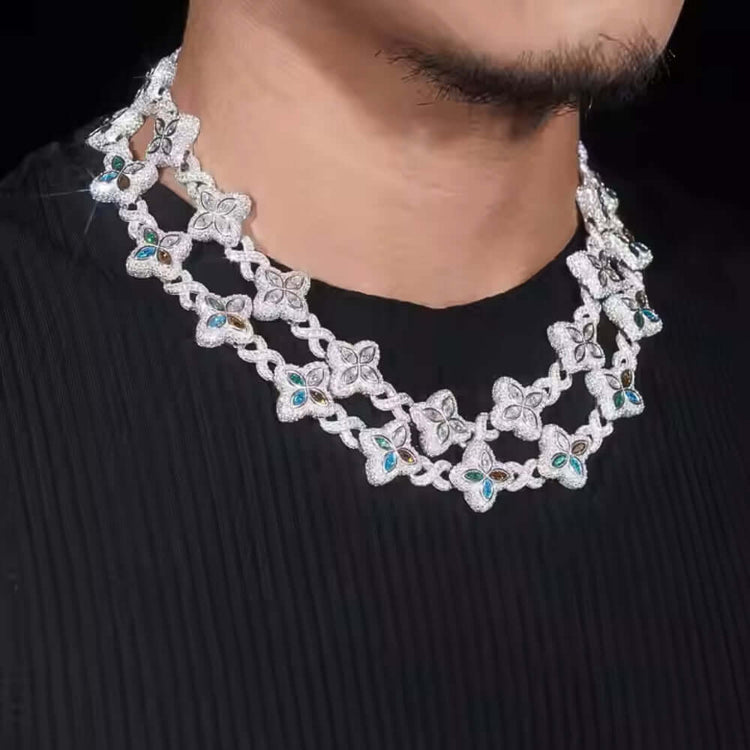 A person wearing the Silver Clover Moissanite Chain, featuring double layers with floral designs and teal gemstone accents, set against a black pleated top.