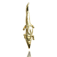 The Crocodile Pendant - 14k Solid Yellow Gold is shown from above against a white background with a subtle reflection beneath it.
