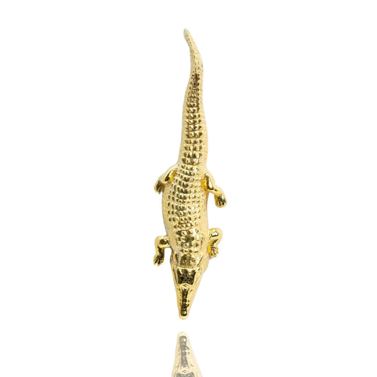 A Crocodile Pendant - 14k Solid Yellow Gold is displayed from above on a white background, with its reflection below—evoking elegant yellow gold jewelry collections.