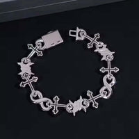 The Cross Infinity Link Moissanite Bracelet, crafted in sterling silver with alternating cross and butterfly charms plus an infinity symbol, is displayed on a black surface.