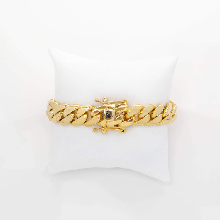 The Handmade Miami Cuban Link Bracelet in solid gold features a central F emblem, is handcrafted in Miami, displayed on a white cushioned pillow against a white background, and is ready to ship.