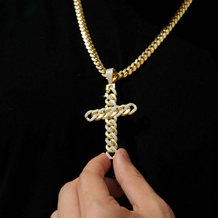 A hand holds the Lab Diamond Cuban Link Cross Pendant, featuring gold and lab diamonds on a thick Cuban link chain, set against a black background.