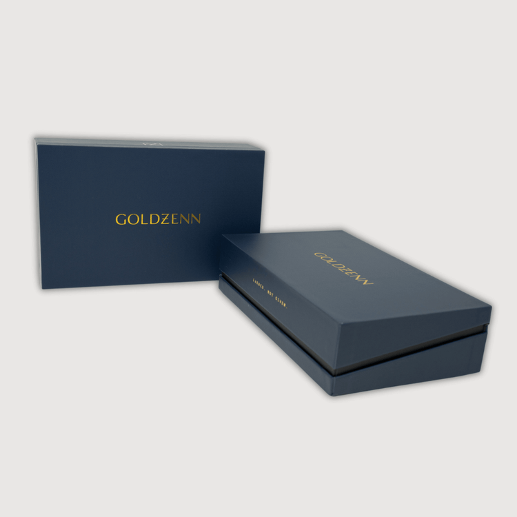 Two elegant, dark blue rectangular boxes with GOLDZENN in gold sit on a light gray background. One box is closed; the other is partially open, revealing a Rope Chain with Custom Diamond Lock - 4mm 14k Gold inside.
