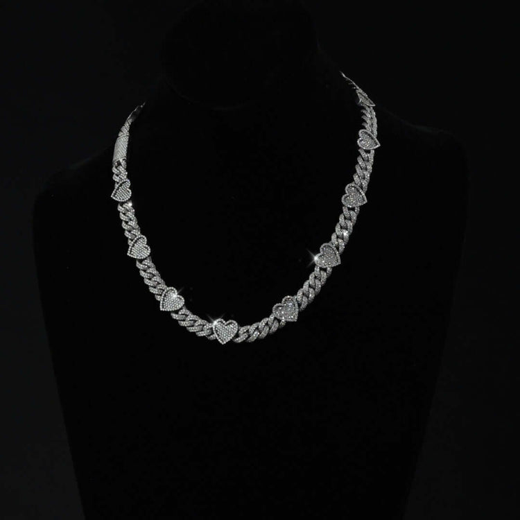 The Diamond Chain - Heart Shaped 10k White Gold features alternating heart and oval links set with natural diamonds, elegantly displayed on a black velvet bust against a dark background.