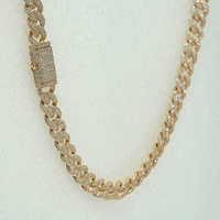 The Diamond Cuban Link Chain – 11mm in 10k solid gold features a box clasp and is fully encrusted with sparkling lab-grown diamonds, shown against a textured white background.