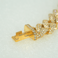 Close-up of the Diamond Cuban Link Chain – 11mm, showcasing its 10k solid gold clasp adorned with sparkling lab-grown diamonds on a white textured surface.