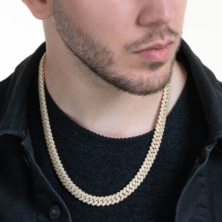 A man wears the Diamond Cuban Link Chain Prong in solid yellow gold over a black shirt and dark jacket, shown from the shoulders up with his face partially visible against a plain white background.