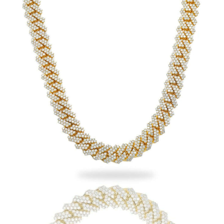 The Diamond Cuban Link Chain Prong in solid yellow gold features a detailed, twisting design adorned with sparkling diamonds, displayed on a white background with its reflection shown below.