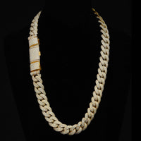 The Diamond Cuban Link Chain - Semi Solid - 16mm is a 10k gold chain encrusted with lab-grown diamonds, displayed on black velvet, and features a rectangular diamond-encrusted clasp on one side.