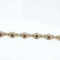 The Diamond Evil Eye Gemstone Bracelet in 10k yellow gold features alternating oval red and blue gemstones, each bordered by small natural diamonds, shown on a white background.