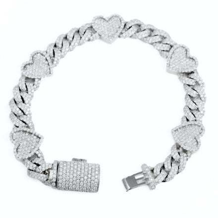 The Diamond Heart Cuban Link Bracelet features thick, interlocking links and heart-shaped charms encrusted with sparkling diamonds, displayed on a white background.