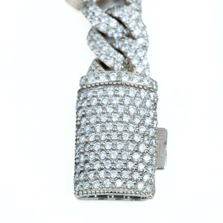 Close-up of a silver clasp encrusted with rows of round diamonds on the Diamond Heart Cuban Link Bracelet, attached to its twisted, diamond-studded chain and shown against a white background.