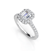The Emerald-Cut Halo Lab Diamond Engagement Ring with Pavé Band showcases an emerald-cut lab-grown diamond, a halo of smaller diamonds, and pavé-set stones along the band, beautifully displayed on a white background.