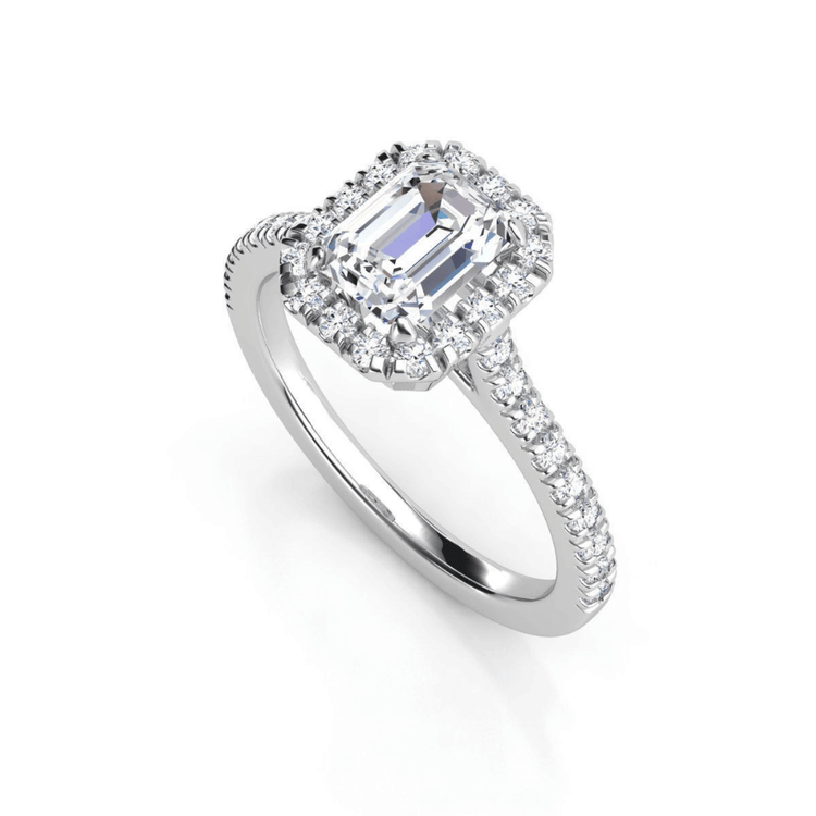 The Emerald-Cut Halo Lab Diamond Engagement Ring with Pavé Band showcases an emerald-cut lab-grown diamond, a halo of smaller diamonds, and pavé-set stones along the band, beautifully displayed on a white background.