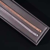 An Emerald Cut Moissanite Tennis Bracelet sparkles elegantly, displayed on a dark rectangular surface with a sleek black background.