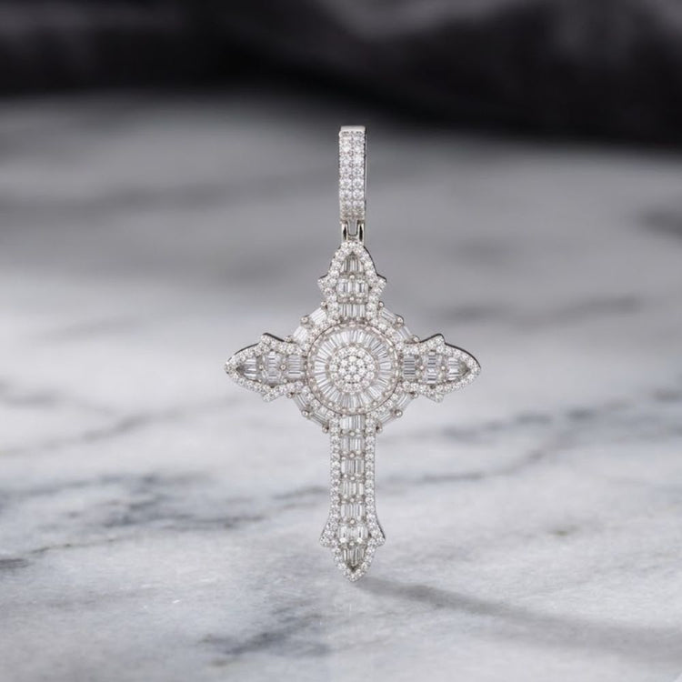 The 925 Silver Mens Moissanite Cross Pendant, featuring diamond-like sparkle and intricate craftsmanship, stands upright on a marble surface against a softly blurred dark background.