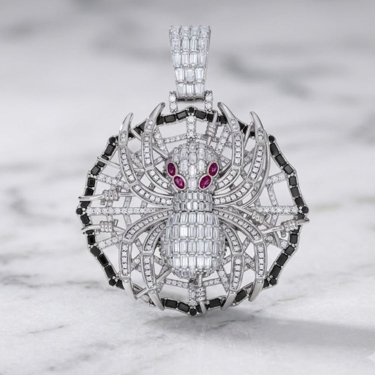 A dazzling 925 Sterling Silver Men's Moissanite Spider Pendant, featuring red gemstone eyes and a web-inspired circular backdrop adorned with silver and diamonds, elegantly displayed on marble—an exquisite piece of wildlife insect jewelry.