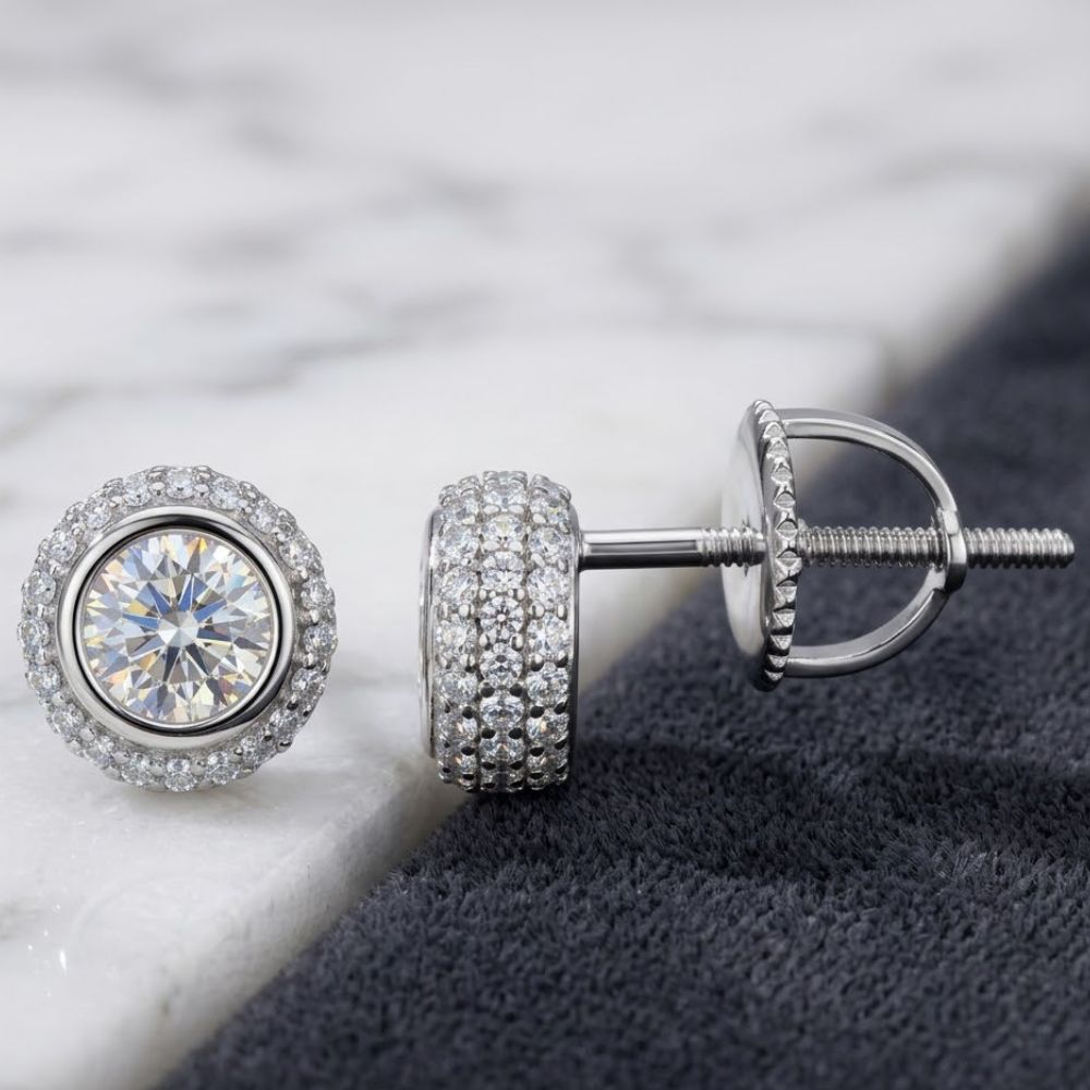 Close-up of 925 Sterling Silver Moissanite Round Stud Earrings featuring large central moissanite stones surrounded by smaller accents, elegantly displayed on marble and dark fabric.