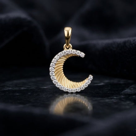 The 1/8CTW Diamond Moon Pendant in 10K Yellow Gold is displayed on a dark, textured surface with a soft black fabric background.