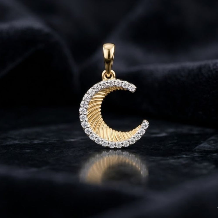 The 1/8CTW Diamond Moon Pendant in 10K Yellow Gold is displayed on a dark, textured surface with a soft black fabric background.