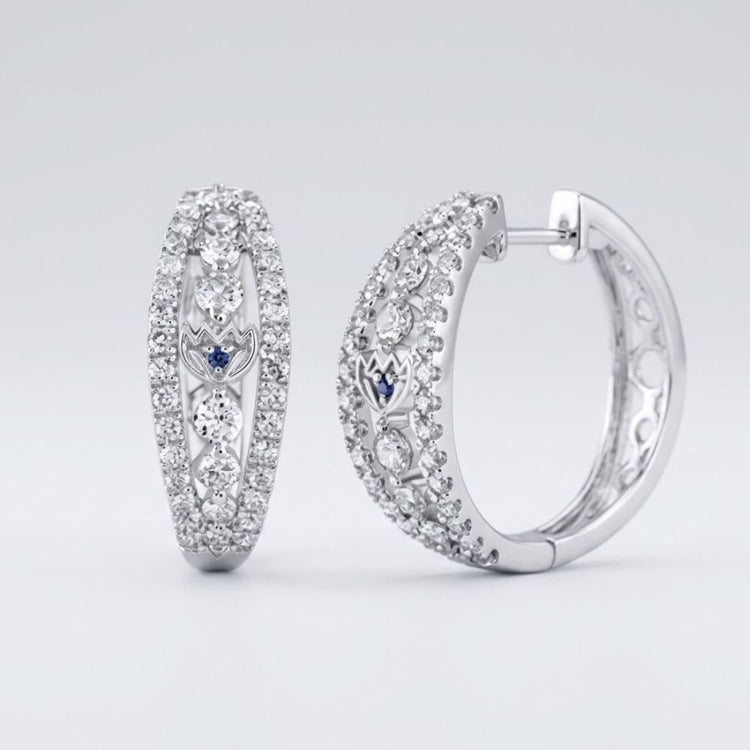 The 14k White Gold Diamond Hoop Earrings (1-1/4 Cttw) feature sparkling diamonds with small blue accents, shown on a light gray background.