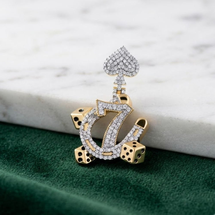 The 10K Gold Diamond 7 Lucky Men’s Charm 1/2CTW features a spade symbol and sparkling stones, surrounded by four gold dice, all resting on a green and white marble surface—a bold statement for men.