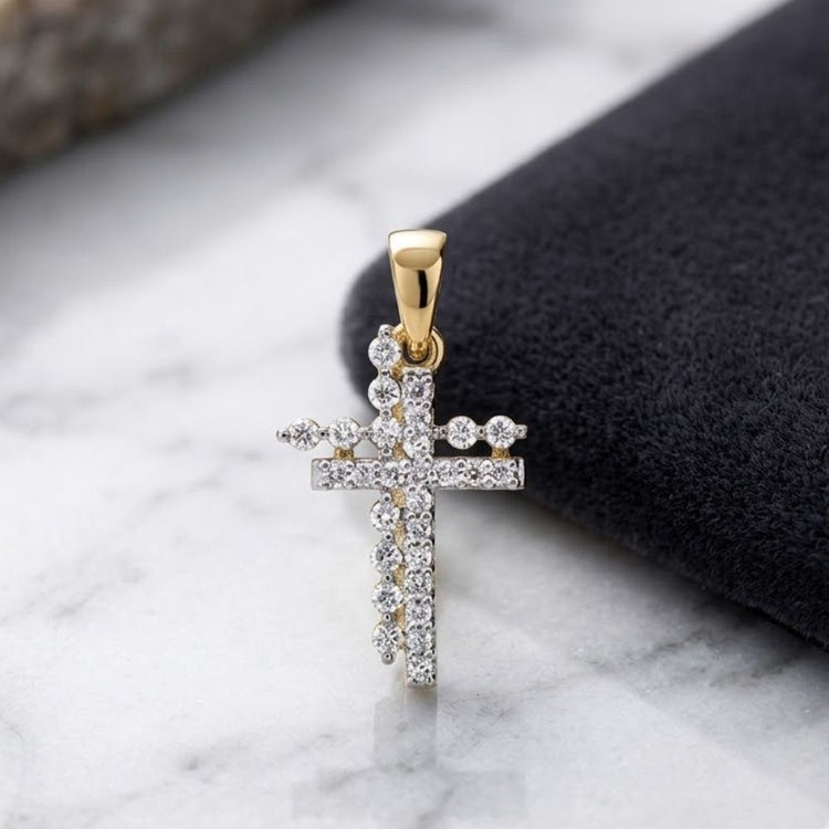 The 10K Yellow Gold 1/5 CTW Natural Diamond Cross Pendant, adorned with shimmering natural diamonds, is elegantly displayed on a black fabric surface with a hint of marble in the background.