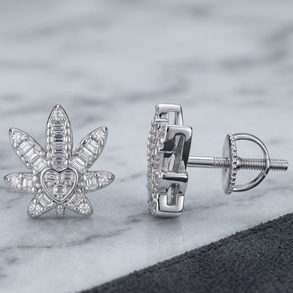 Sterling Silver Moissanite Leaf Stud Earrings are displayed on a gray marble surface with a partial black accent. A chic addition to women’s fashion jewelry collections.