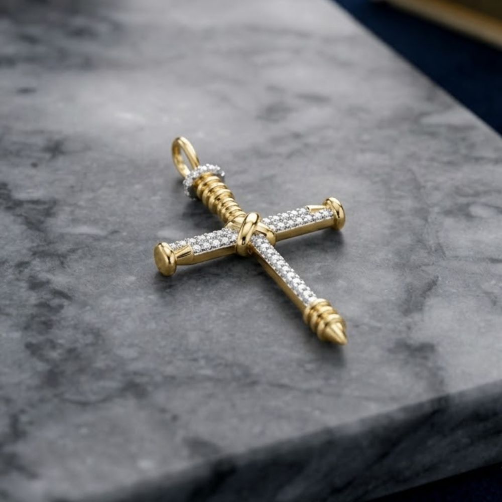 The 10K Gold Diamond Nail Cross Charm Pendant 1/5 CTW, featuring two nails bound together and adorned with sparkling diamonds, rests on gray marble—a striking faith-inspired jewelry piece.