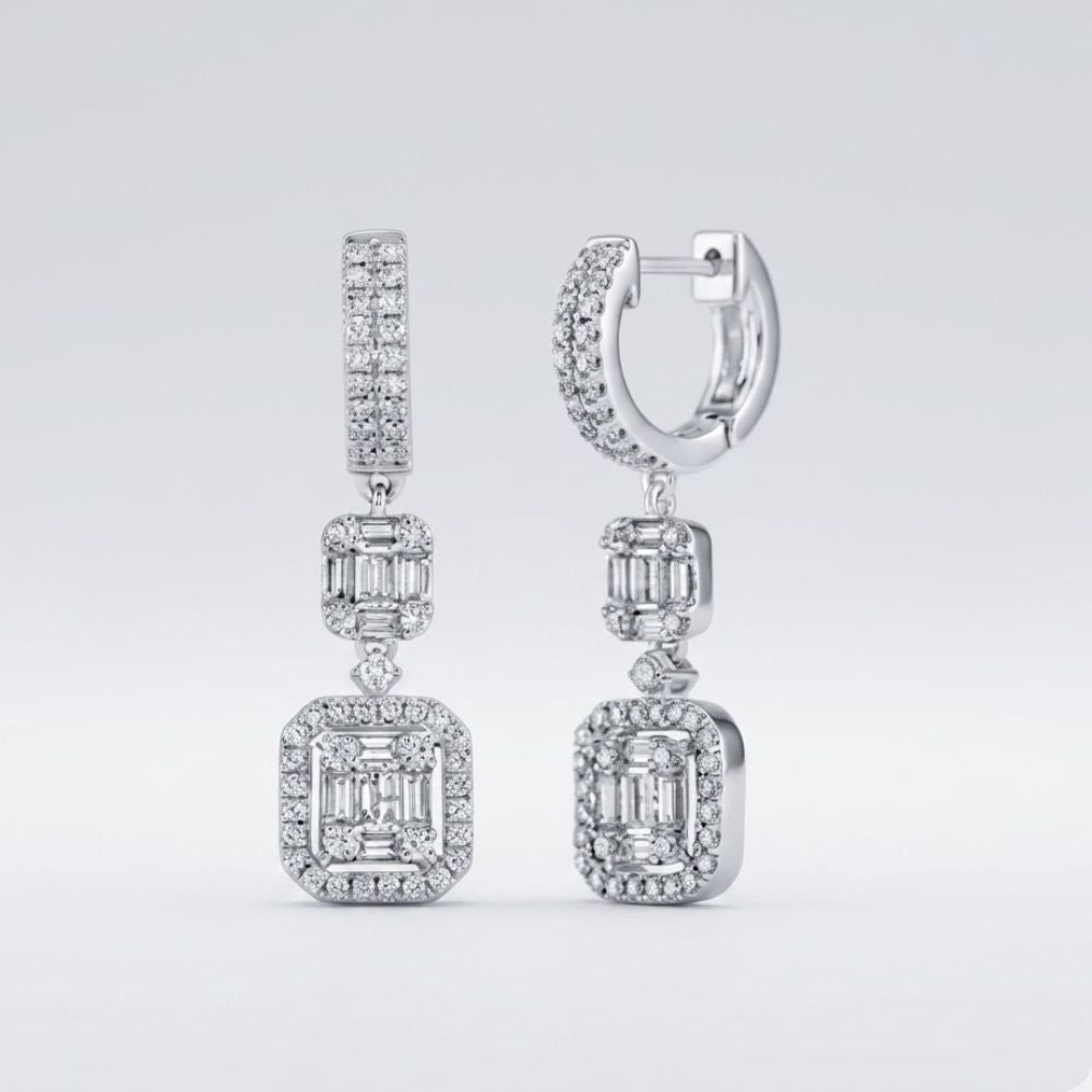 The 1 Cttw 14k White Gold Baguette Diamond Dangle Earrings feature rectangular baguette diamond clusters framed by smaller diamonds, suspended from diamond-studded hoops against a light gray background.