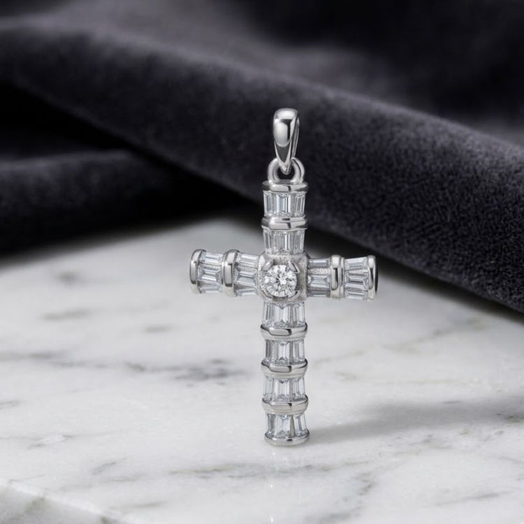 The 925 Sterling Silver Men's Baguette CZ Cross Pendant, adorned with a round central diamond and rectangular baguette cubic zirconia charm accents, rests on a marble surface beside a folded piece of black velvet fabric—a striking example of men's religious jewelry.