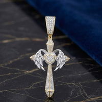 The 1 1/5CTW Natural Diamond Chrome Hearts Cross Charm in 10K gold features angel wings and a diamond heart center, accented with silver and small diamonds—shown on black marble beside dark blue fabric, it's a bold hip hop jewelry piece.
