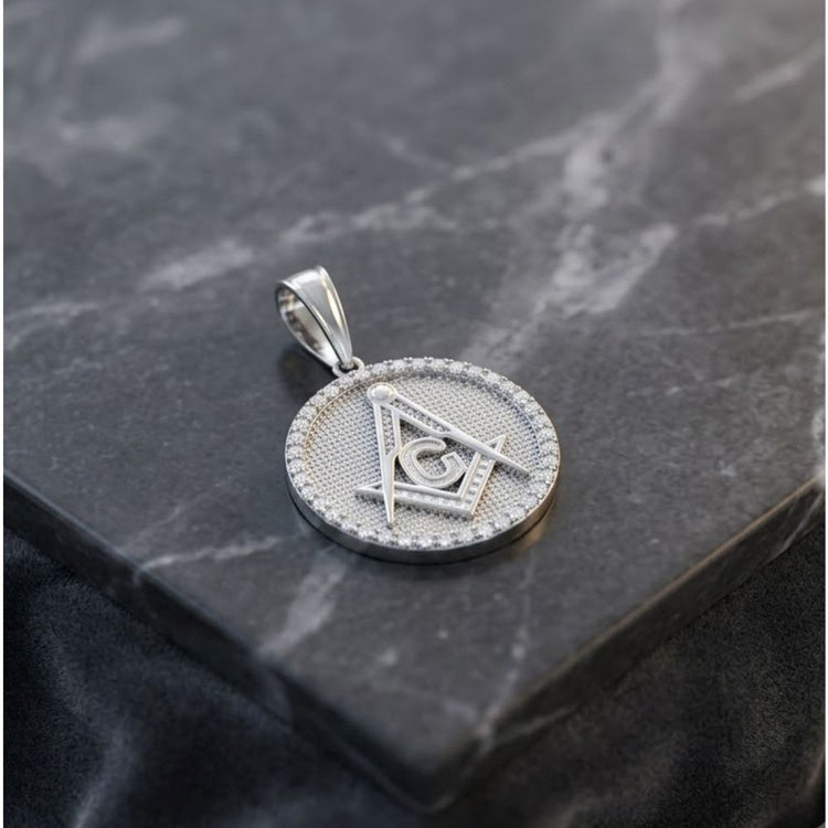 A striking Sterling Silver Cubic-Zirconia Masonic Symbol Pendant, featuring the iconic Masonic square and compass, rests elegantly on a dark marble surface, embodying the timeless craftsmanship of fine Masonic jewelry.