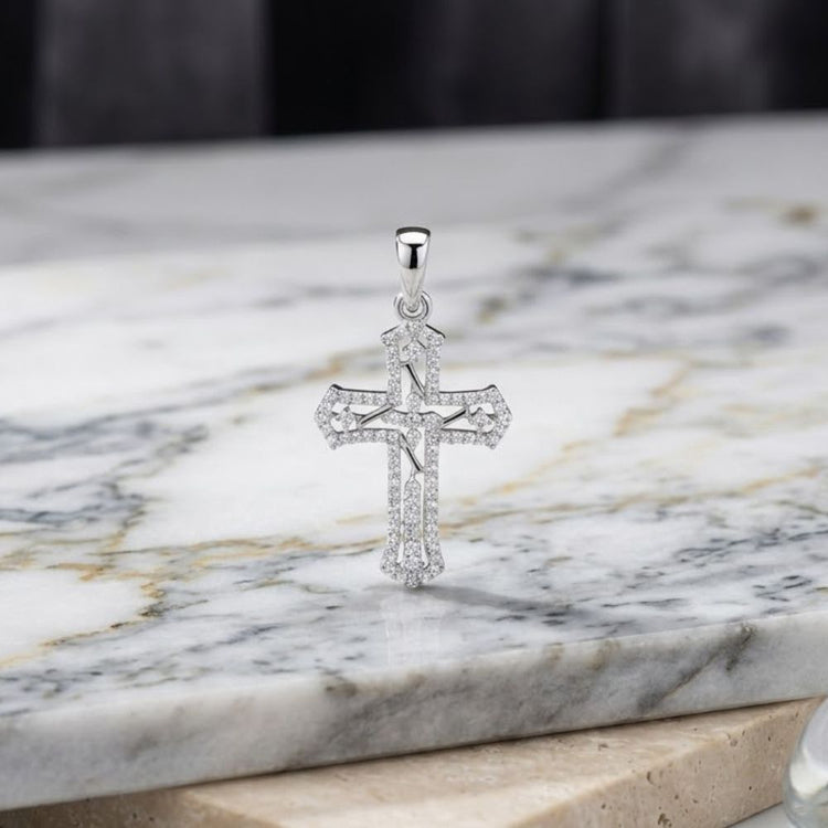 A 1/4CTW Natural Diamond Cross Pendant in sterling silver stands upright on a polished marble surface, its sparkling diamonds shining against a blurred dark background.