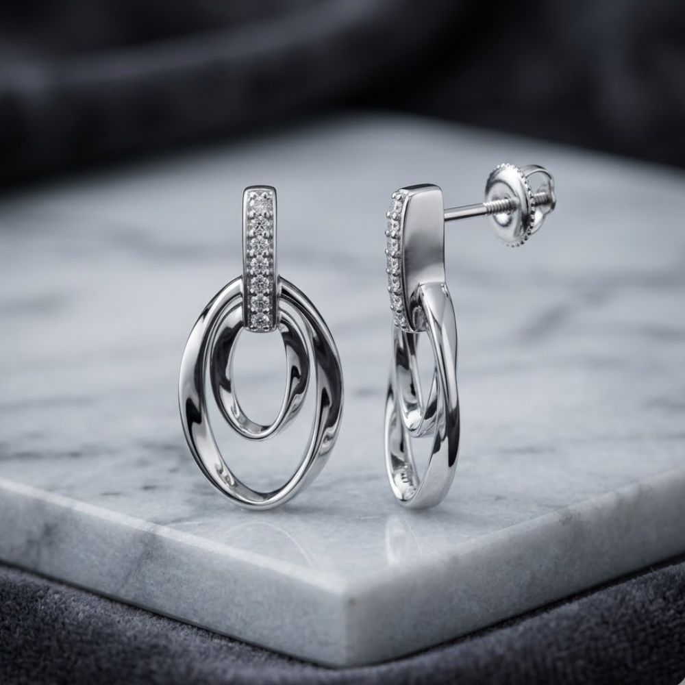 Elegant 1/12 CTW natural diamond gift earrings in sterling silver, featuring interlocking oval loops and sparkling stones, displayed on marble with a dark background—perfect for a sophisticated touch.