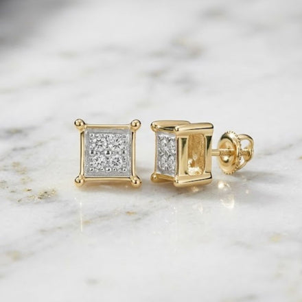 The 10k Yellow Gold Diamond Square Earrings .03 Cttw are elegantly displayed on a white marble surface. One earring stands upright to showcase the sparkling diamond pavé front, while the other rests on its side, highlighting both the sleek profile and secure screw-back closure.