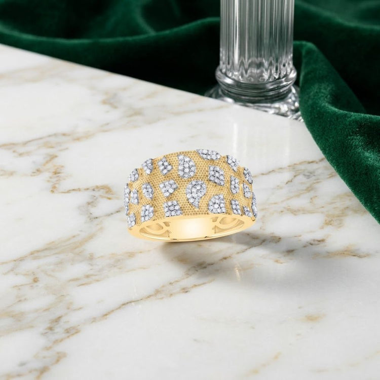 A bold 5/8CTW Natural Diamond Men’s Nugget Ring in 10K gold rests on a white marble surface, placed next to green velvet fabric and a ribbed glass vase.