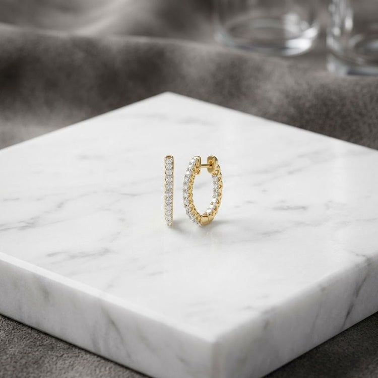 14k Yellow Gold Diamond Inside Outside Hoop Earrings resting on a white marble surface.