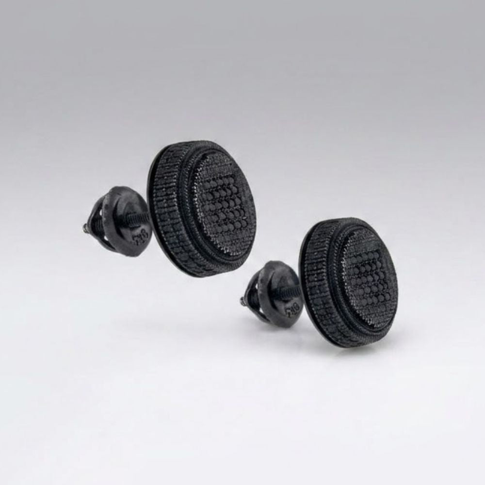 Two black objects resembling Oreo cookies sit against a gray background. On closer inspection, they are actually Black Sterling Silver Diamond Cluster Earrings with a playful, eye-catching design.