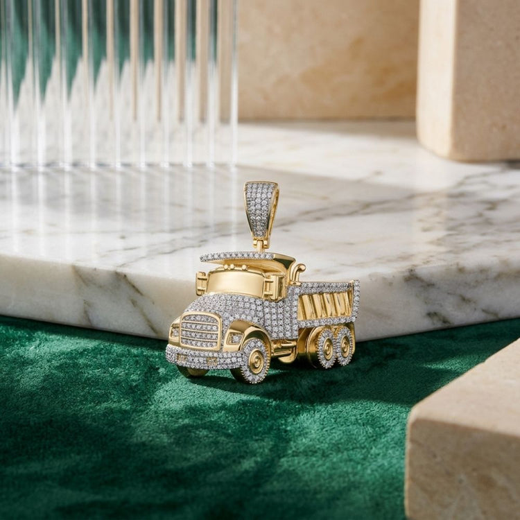 A 7/8 CT diamond truck charm, expertly crafted in 10k yellow gold, rests on a marble surface layered over green velvet and framed by geometric stone accents and glass—a striking men’s piece that radiates bold elegance.