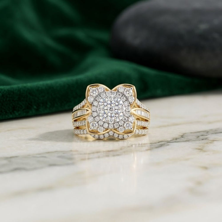 A captivating 1 1/3CTW Natural Diamond Flower Bridal Set in 14k gold is displayed on a marble surface, with a dark green cloth and smooth gray stone in the background.