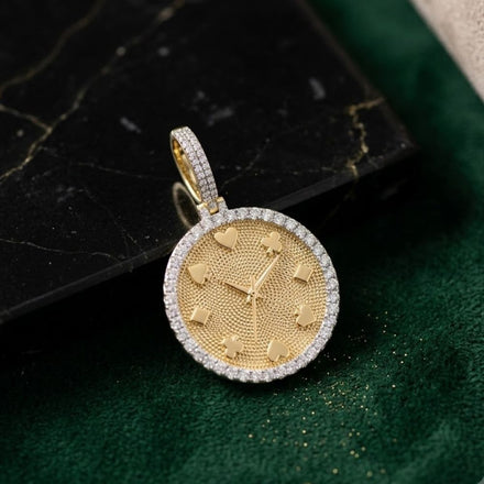 The 10K Gold Diamond Poker Clock Pendant 7/8CTW, crafted in yellow gold with diamond accents and poker-inspired markers, is displayed on a green surface next to a black marble slab.