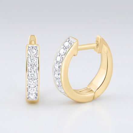 The 10k Yellow Gold Diamond Hoop Earrings 1/6CTW feature a row of sparkling white diamonds on each hoop, shown with one earring facing forward and the other displaying its side view and clasp.