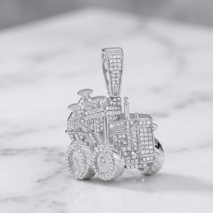 A sterling silver truck charm, adorned with numerous small diamonds (5/8CTW), captures the rugged appeal of men’s natural diamond jewelry and is elegantly showcased on a white marble surface.