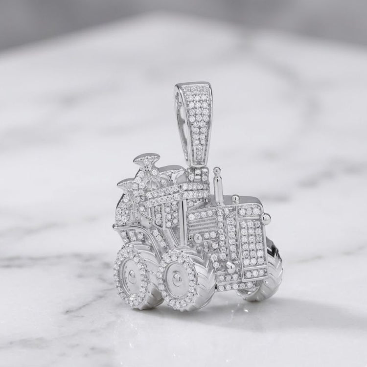 A sterling silver truck charm, adorned with numerous small diamonds (5/8CTW), captures the rugged appeal of men’s natural diamond jewelry and is elegantly showcased on a white marble surface.
