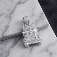 A 1-1/3CTW Diamond Truck Charm in sterling silver, shaped like a crowned truck and resting on a white marble surface against a dark textured background, exemplifies the bold allure of men’s jewelry and the brilliance of natural diamonds.