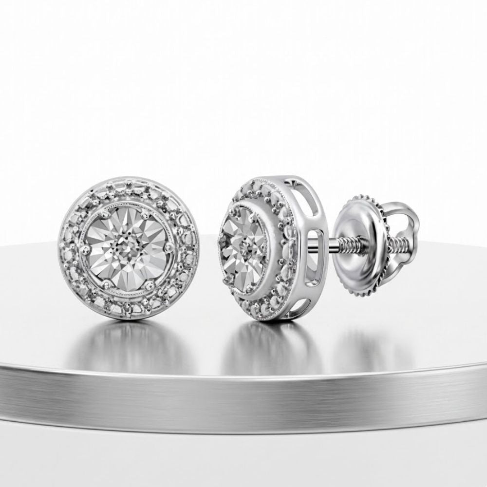 A pair of 0.01CTW Diamond Round Earrings in sterling silver is shown on a reflective circular surface against a white background.