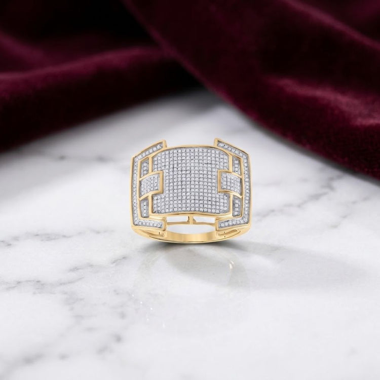 The 10K Yellow Gold Diamond Cluster Ring 5/8 CTTW features geometric cutouts and rows of sparkling diamonds, displayed atop a white marble surface with burgundy velvet draped in the background.