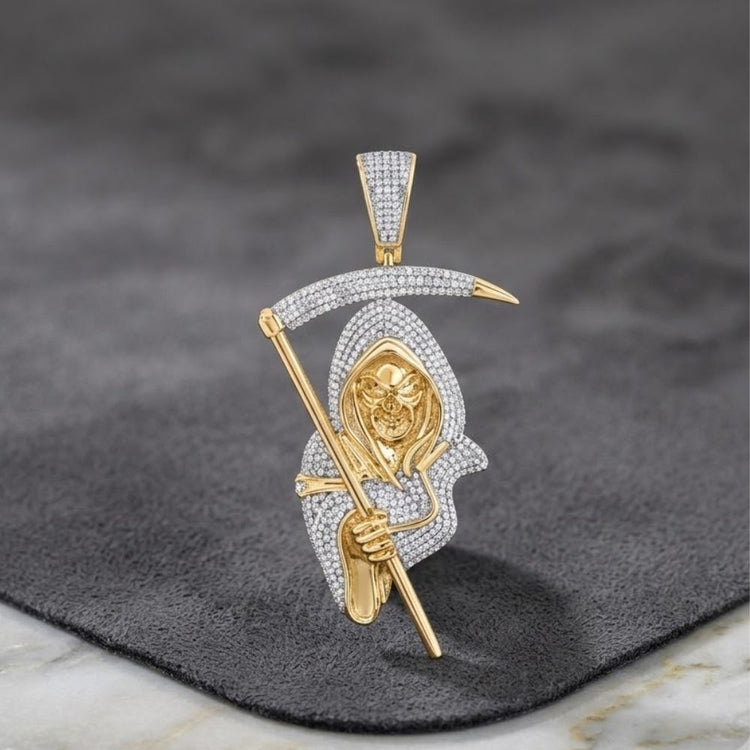 Introducing the 10k Gold Diamond Reaper Men's Charm 2CTW—a bold pendant featuring the Grim Reaper holding a scythe and adorned with sparkling diamonds. Crafted in luxurious yellow gold, this men’s charm makes a statement against a dark gray textured surface, perfectly blending luxury with daring design for fans of standout men's jewelry.